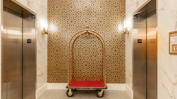 An elevator with a red carpet, a decorative golden wall, and floor tiles.