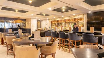 A restaurant with a bar area, seating arrangements, and a chandelier.