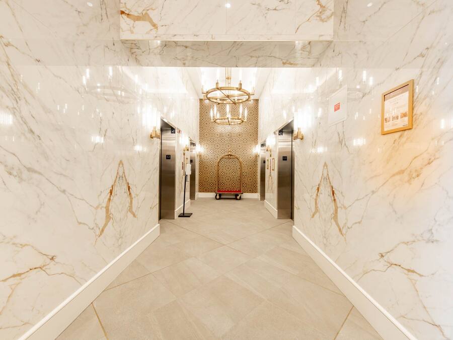 A marble-floored corridor with elevators and a decorative wall at the end.