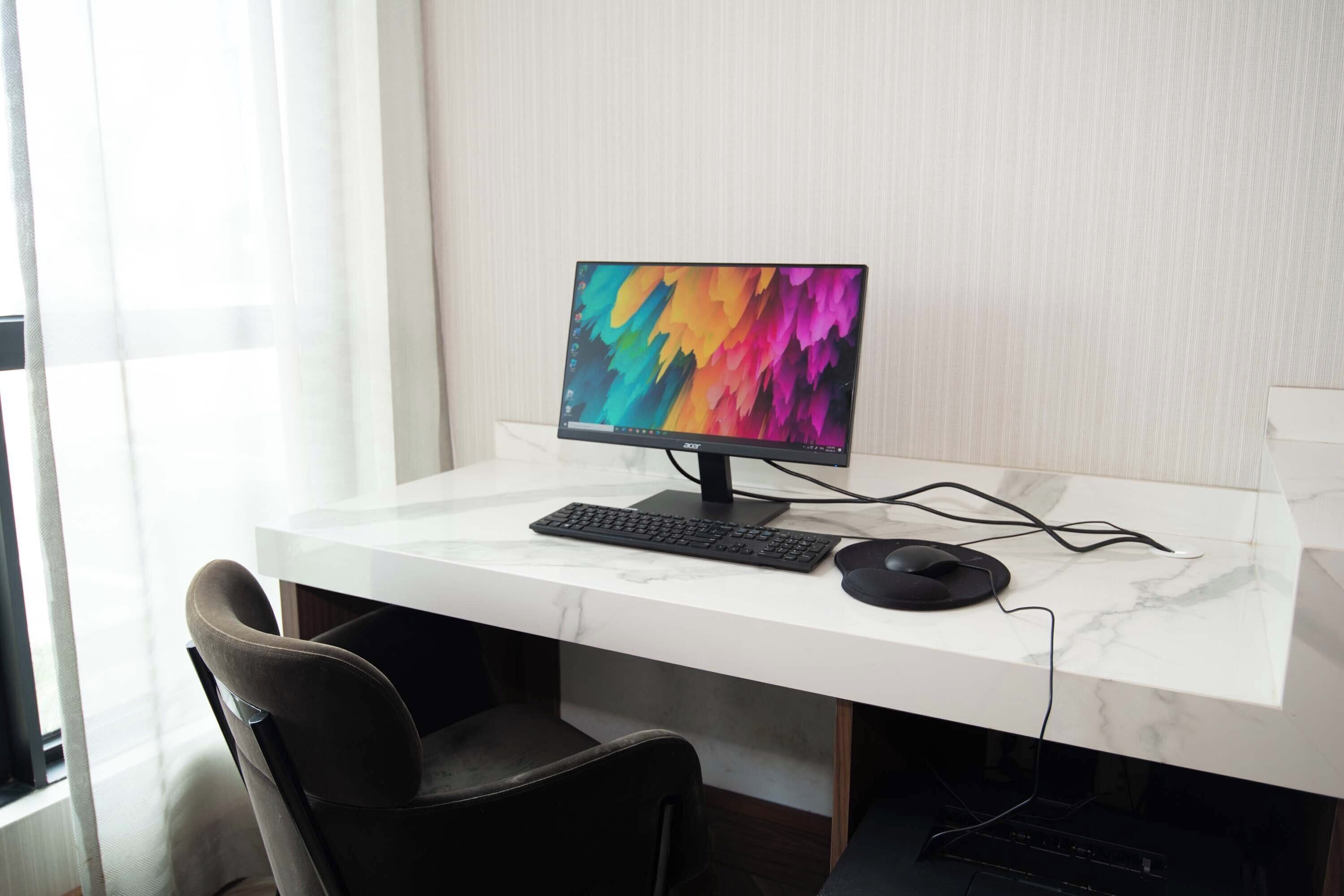 A modern office desk with a computer, keyboard, and mouse.