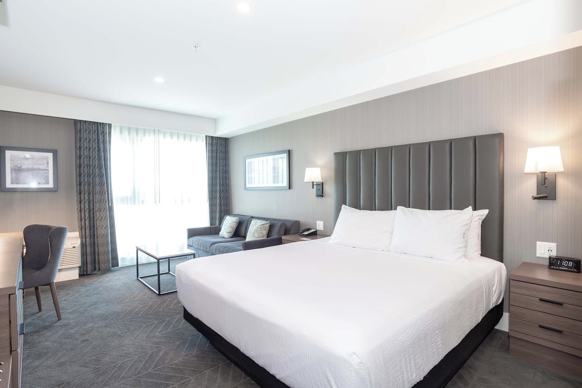 Una habitación de hotel moderna con una cama grande, un sofá, un escritorio y una lámpara.
