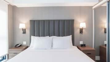 Una habitación de hotel moderna con una cama grande, dos mesitas de noche, una lámpara de pared y un teléfono en una de las mesitas.