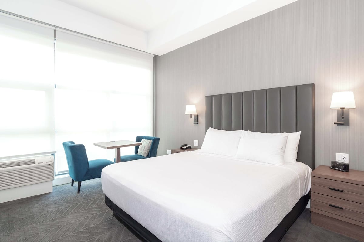 Una habitación de hotel moderna con una cama grande, un escritorio y una silla.
