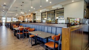 A restaurant with booths and tables, wooden flooring, and pendant lighting. - Sandman Signature Saskatoon South Hotel (Saskatoon)