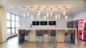 A modern kitchen with a central island, bar stools, pendant lighting, and a Coca-Cola refrigerator. - Sandman Signature Saskatoon South Hotel (Saskatoon)