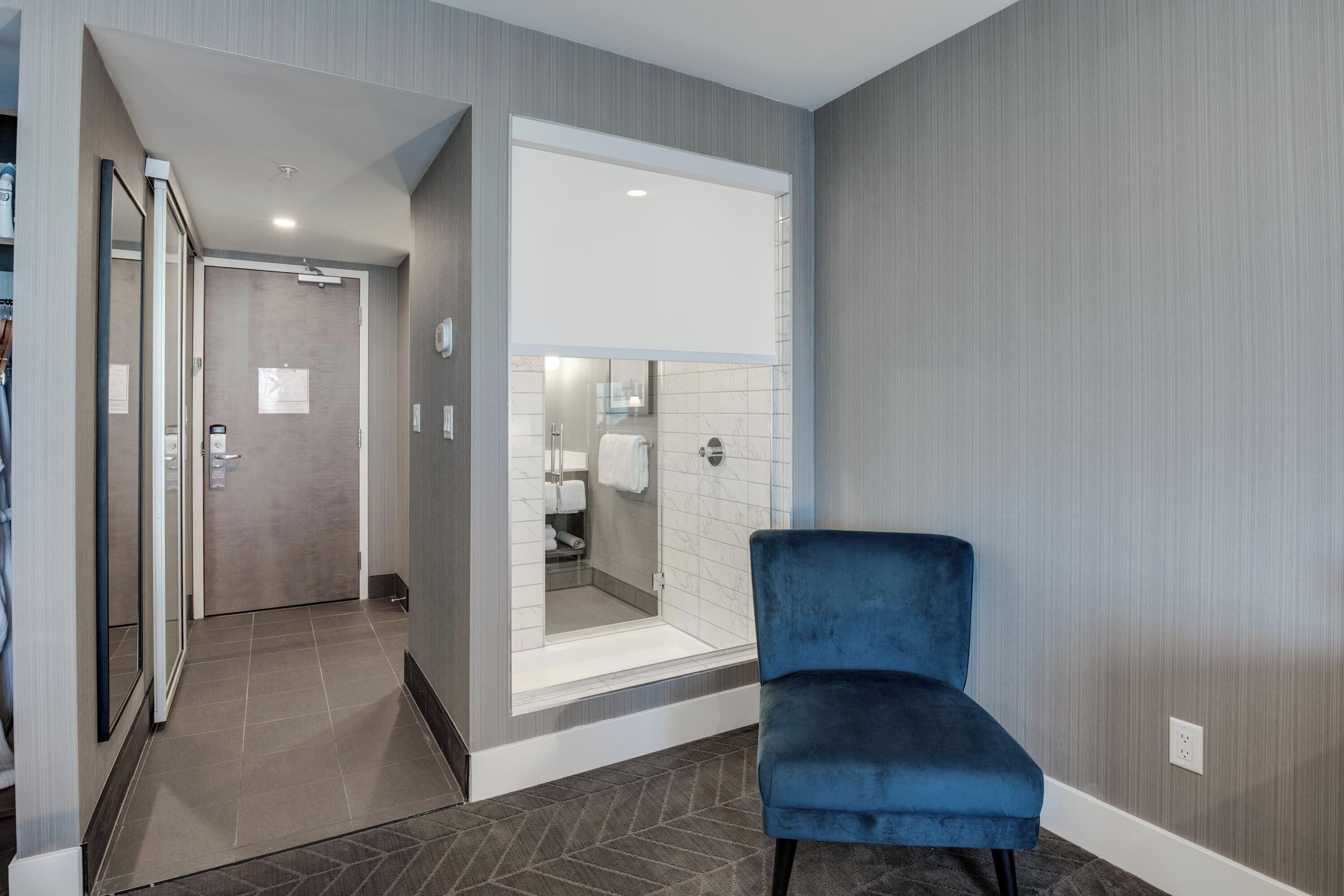 Une salle de bain moderne avec une douche à parois de verre, un porte-serviettes et une chaise bleue dans un coin.