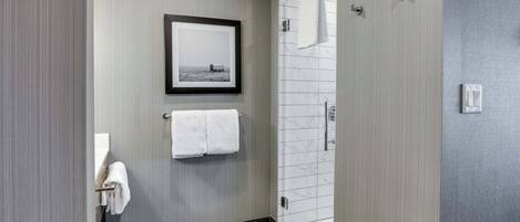 A modern bathroom with a shower, a framed picture on the wall, and a towel rack.