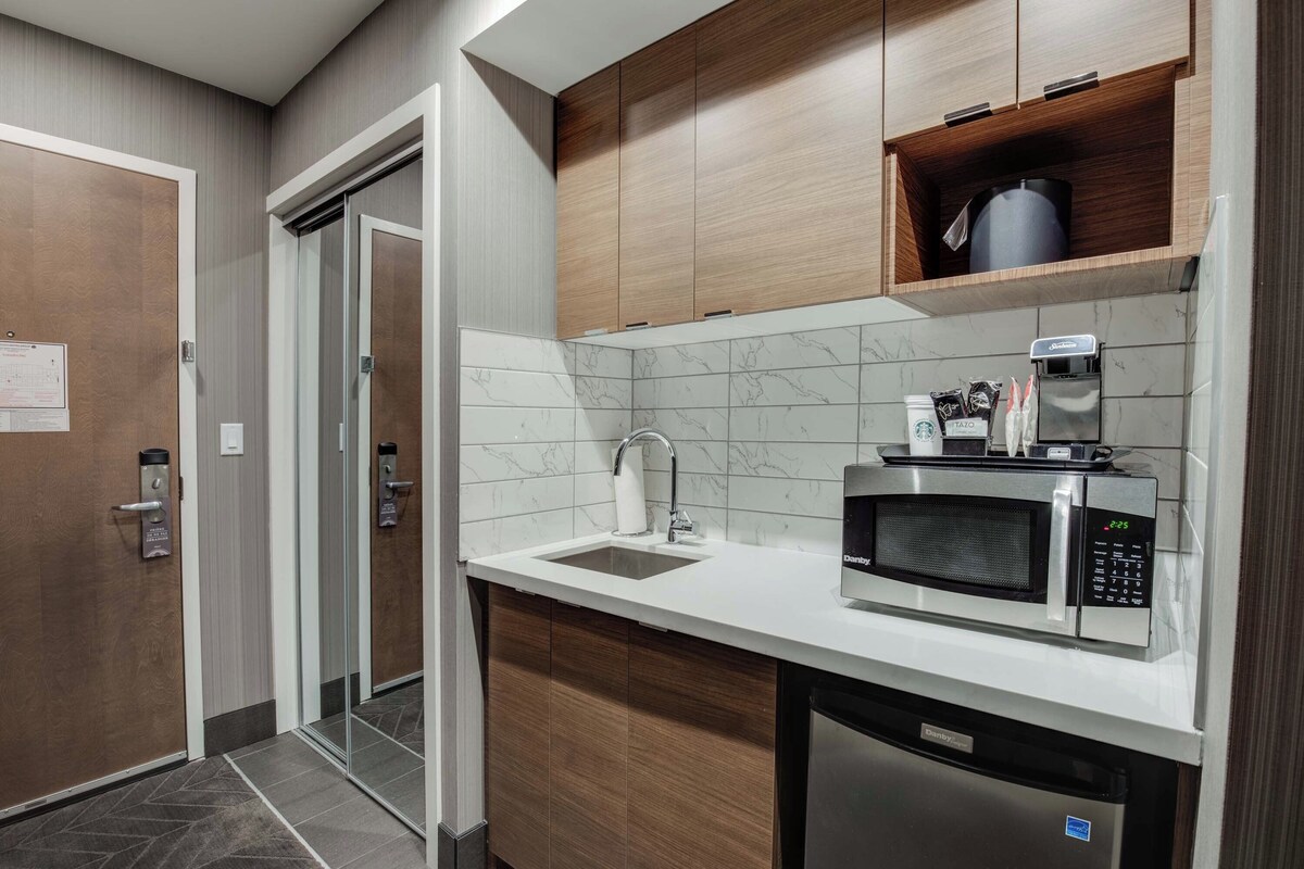 A compact kitchen with a built-in microwave, a coffee machine, and a dishwasher.