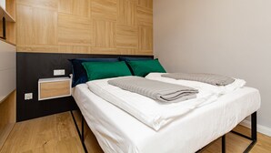 Un dormitorio con cama, mesita de noche y cabecera de madera.
