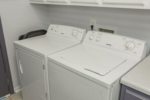 A laundry room with two white front-loading washing machines and a dryer.