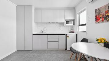 Una cocina moderna con armarios blancos, un microondas y un comedor con una mesa y sillas.