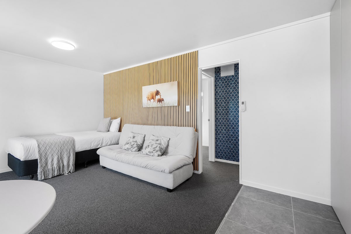 A modern, compact room with a bed, a sofa, and a small table.