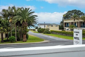 A street view with a motel sign, palm trees, and a building with a balcony.