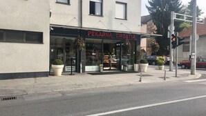 Een winkelgevel met een bord waarop 'PERKARNA CROATIA' staat en grote potplanten ervoor.