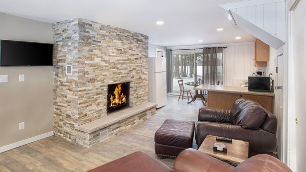 Una sala de estar con chimenea de piedra, sofá de cuero y televisor de pantalla plana.
