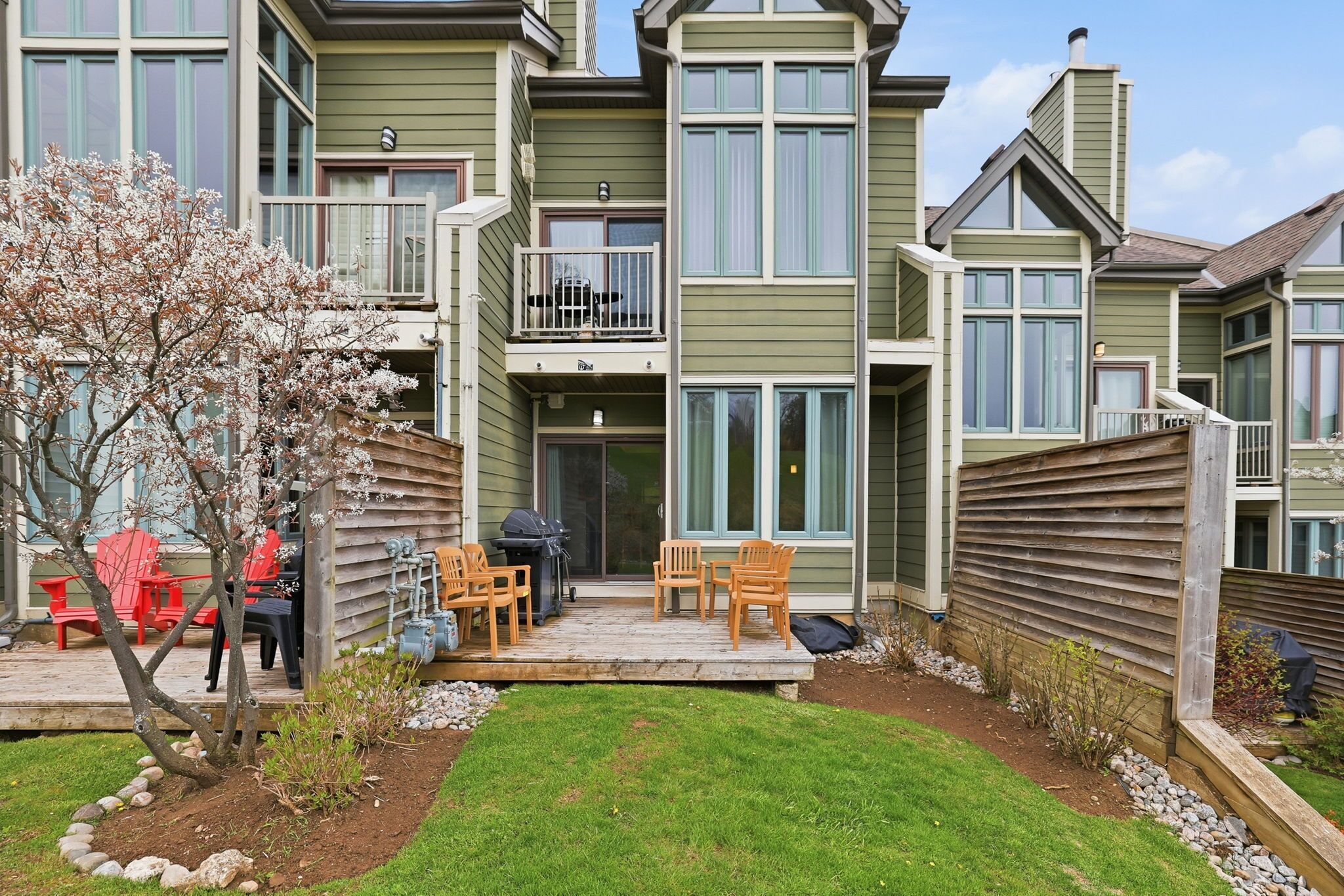 Un immeuble résidentiel à plusieurs étages doté d’un patio, d’un espace extérieur aménagé pour s’asseoir et d’un petit jardin.
