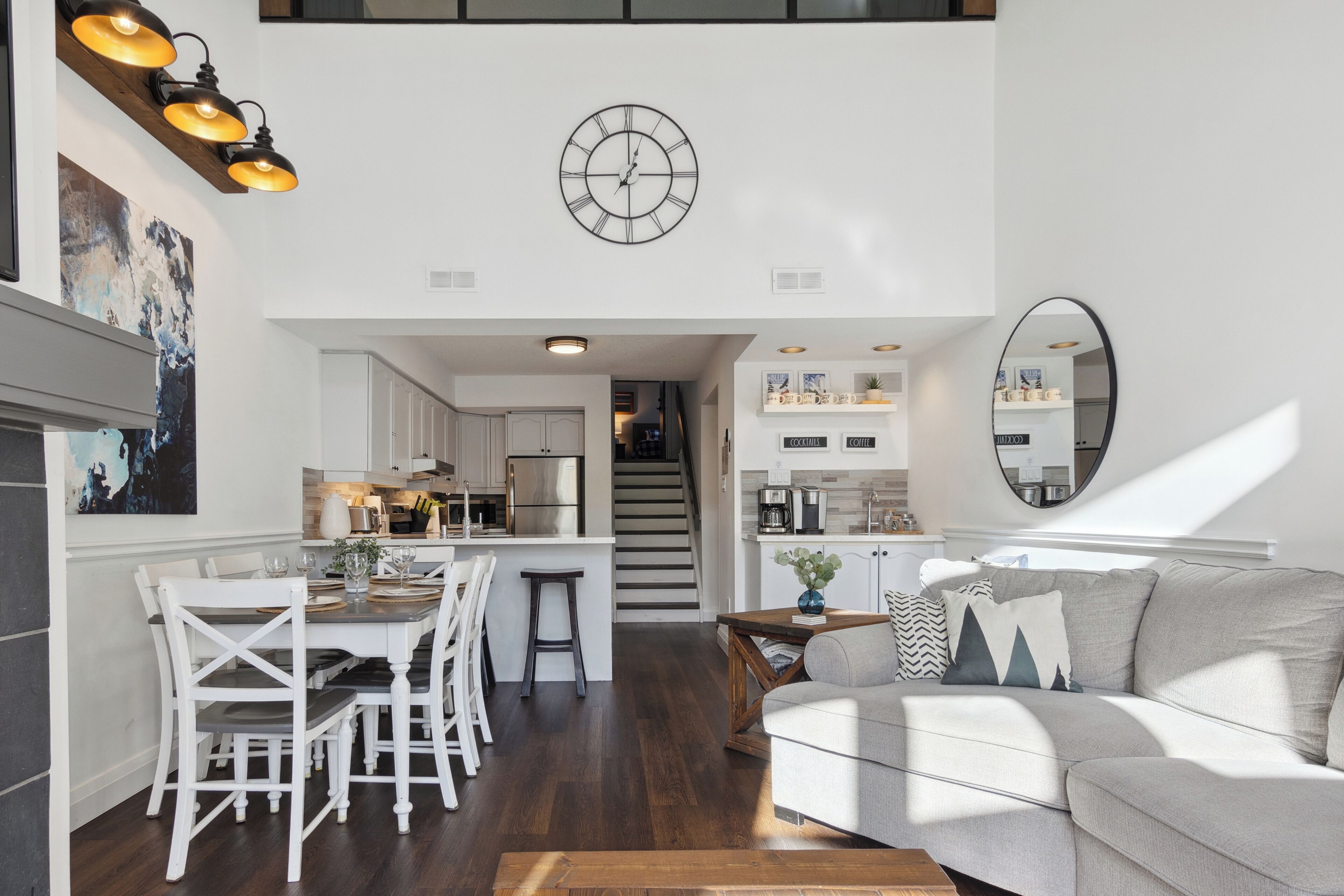 Une cuisine moderne avec des meubles blancs, un îlot central et un coin repas avec des chaises blanches.