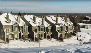 A row of modern, multi-story buildings with large windows and a flat roof, surrounded by snow.