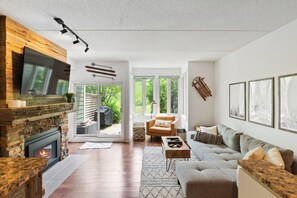 A modern living room with a fireplace, a large TV, and a comfortable seating area.