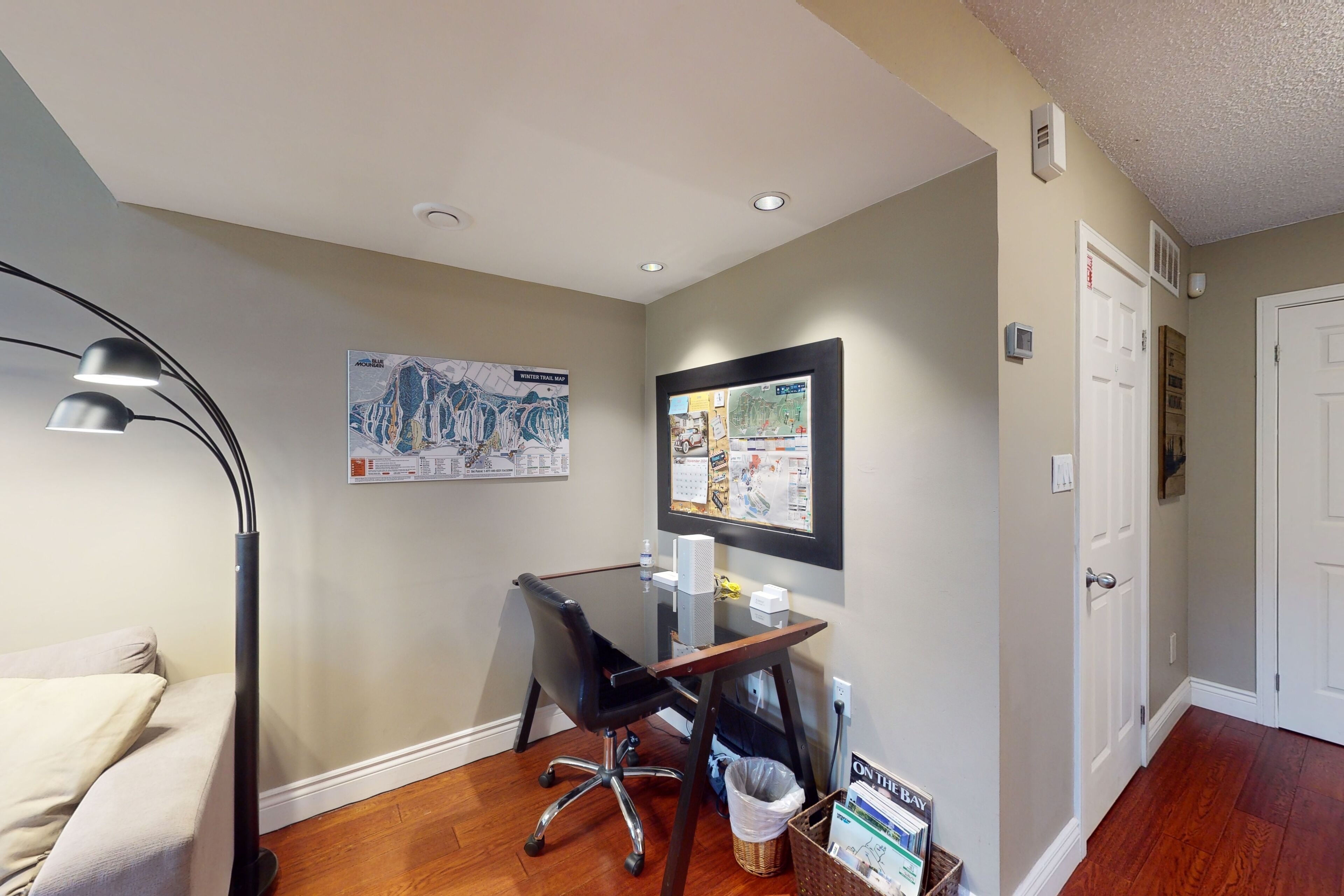 A small office with a glass desk, black office chair, and a map on the wall.