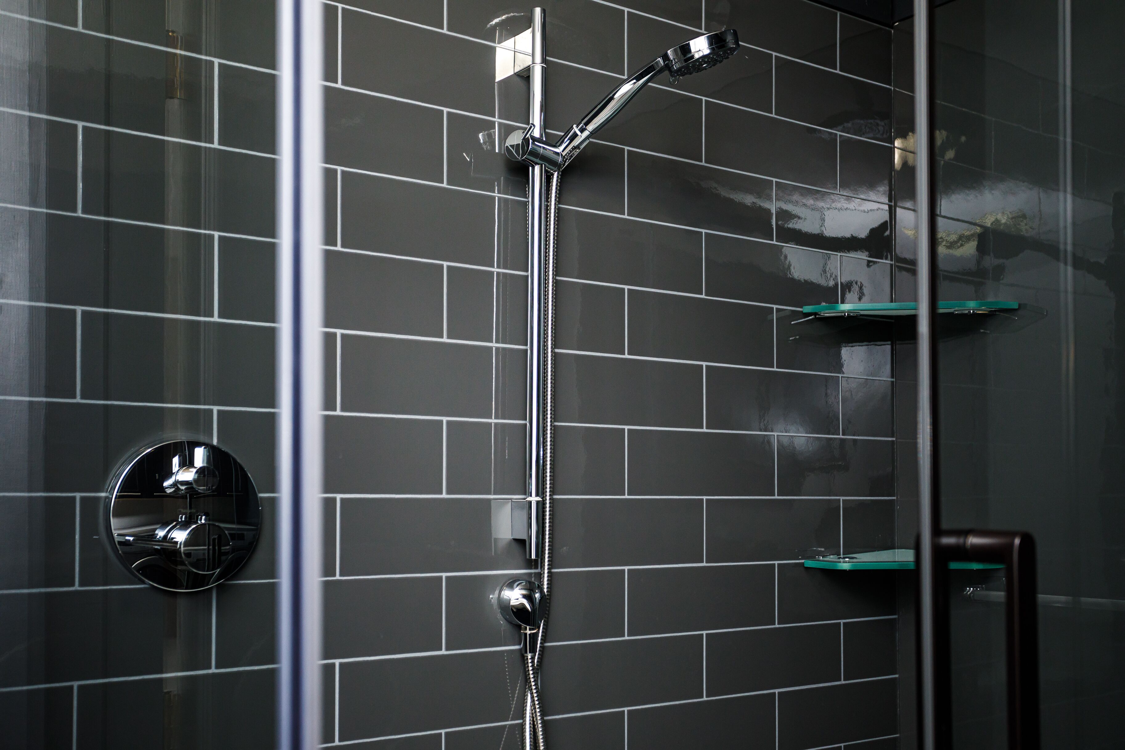 Eine Dusche mit chromfarbenem Wasserhahn und einer Glastür.