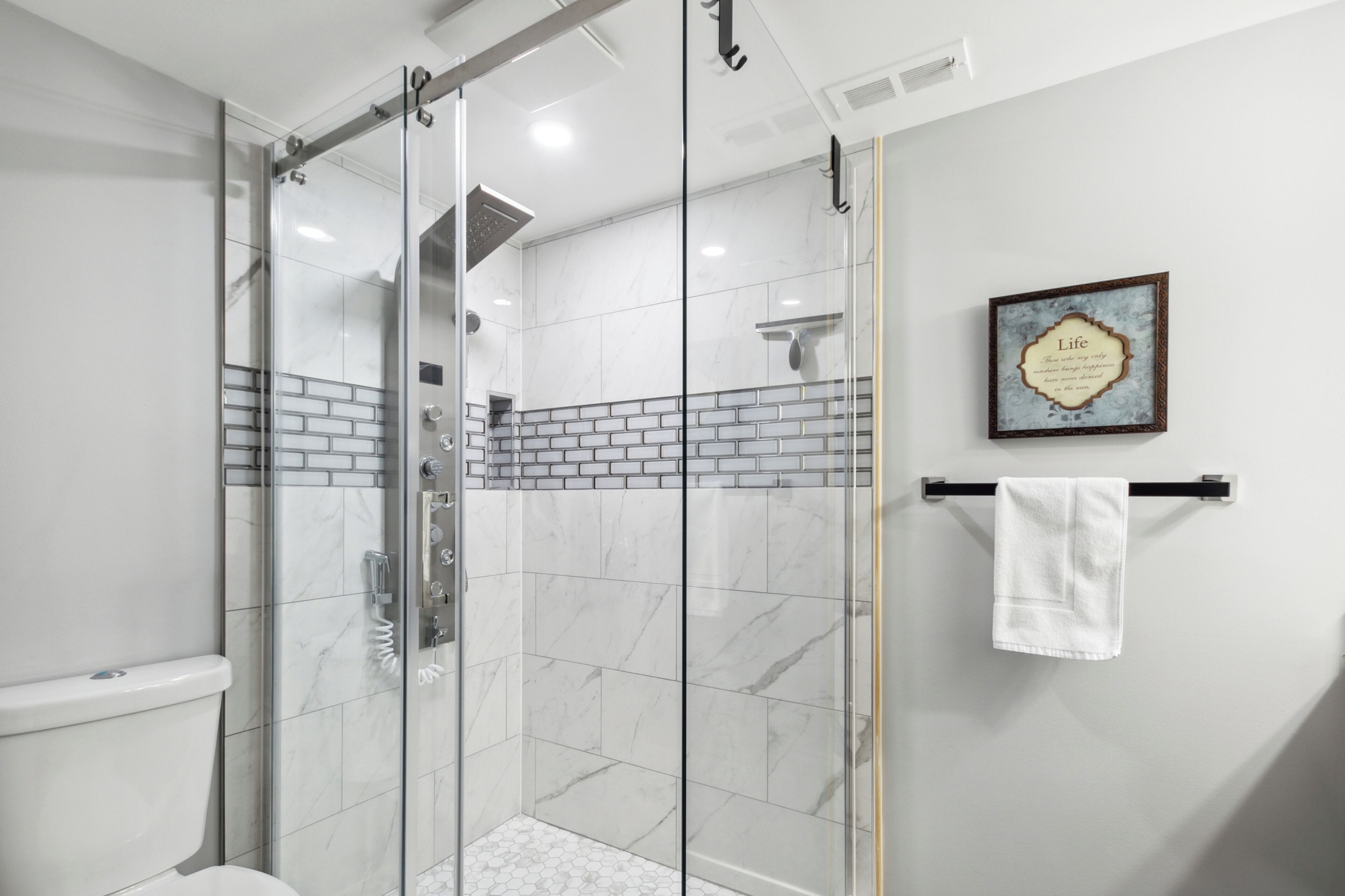 A modern bathroom with a glass-enclosed shower, a white toilet, and a tiled floor.