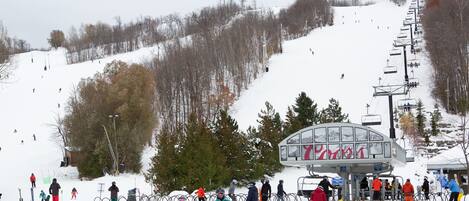 Une station de ski dotée d'un télésiège, de pistes de ski et d'un chalet.