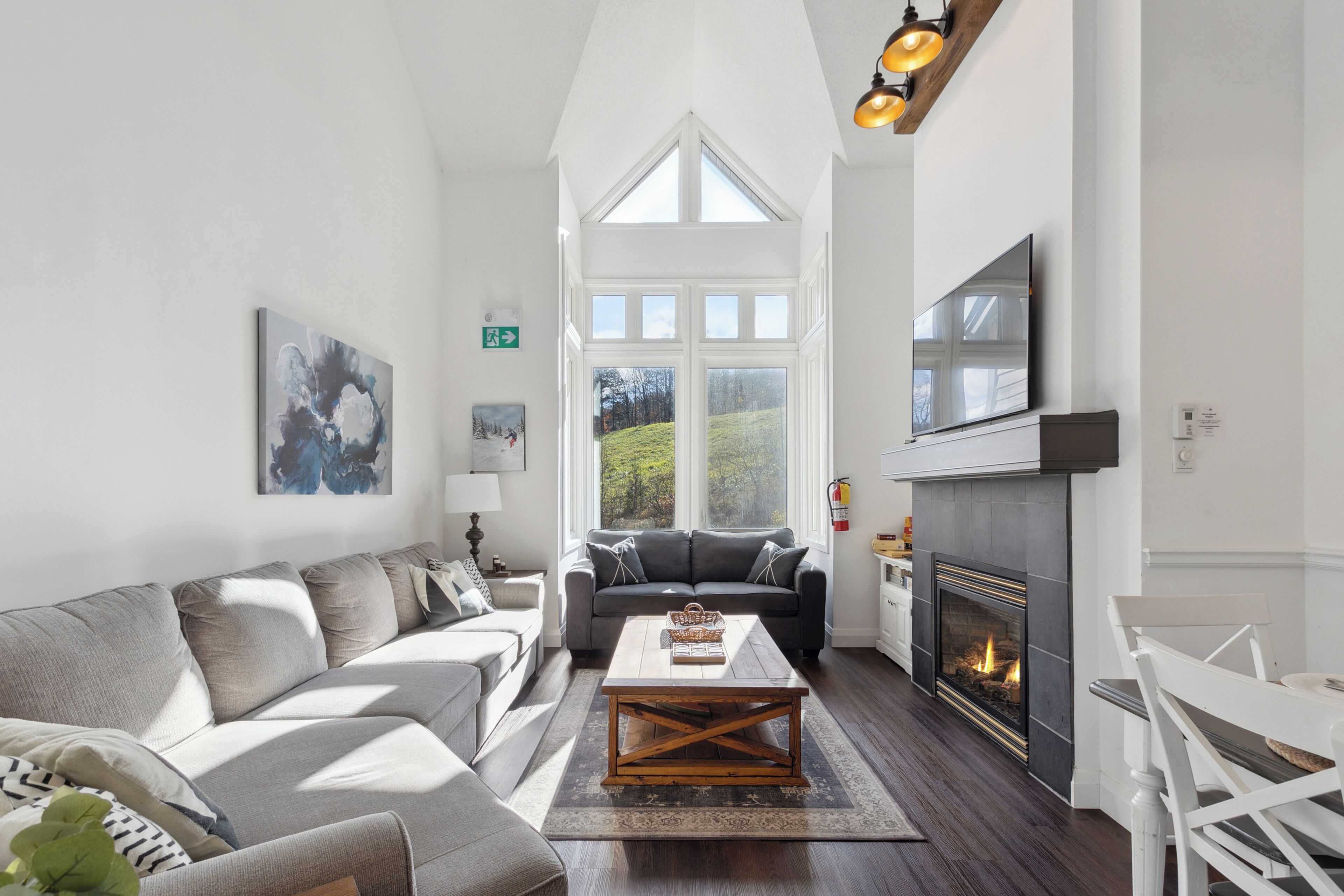 A spacious living room with a fireplace, a large window, and a cozy seating area.