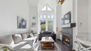 A spacious living room with a fireplace, a large window, and a cozy seating area.