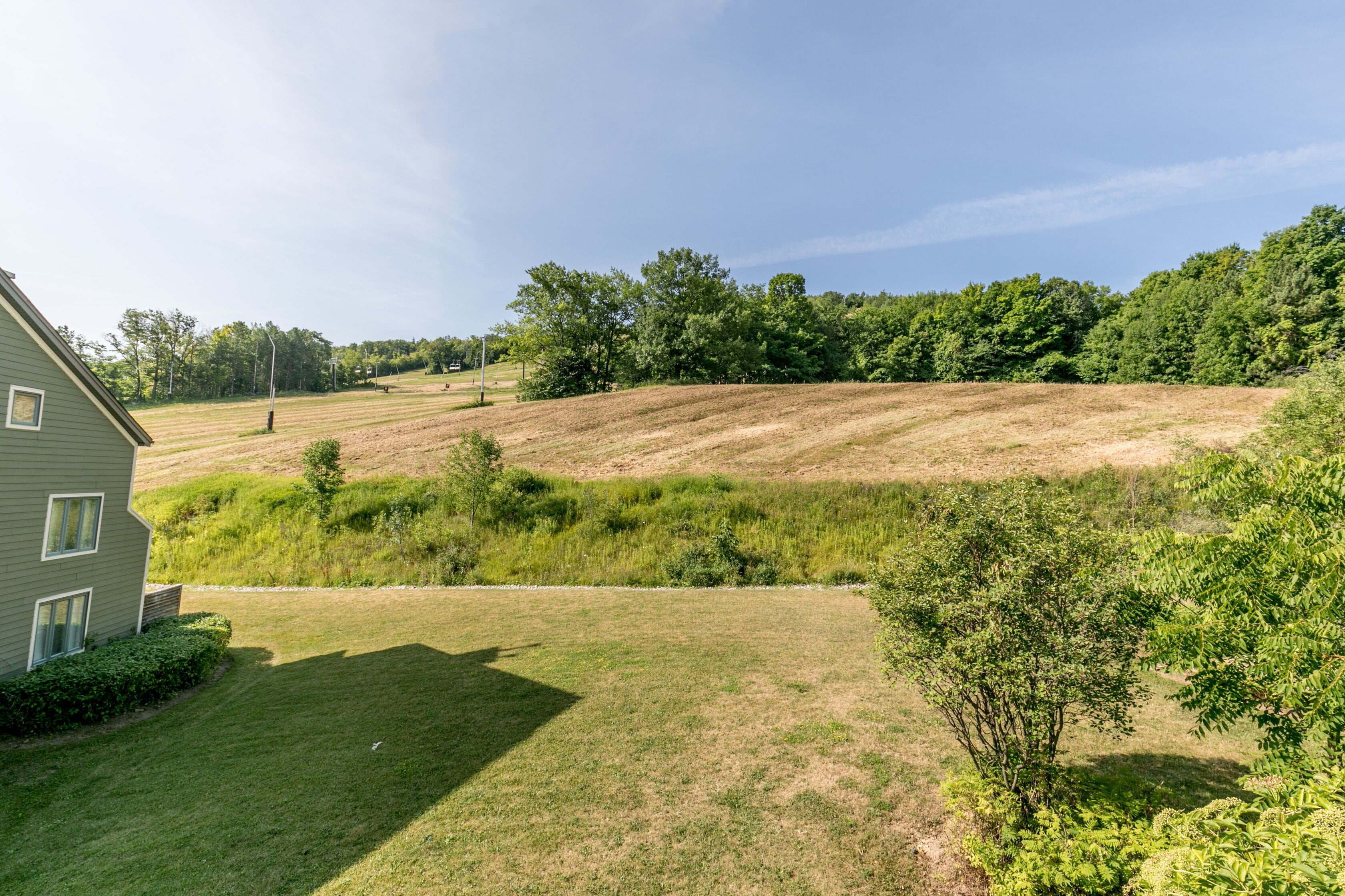 A house with a well-maintained lawn and a hilly landscape in the background.