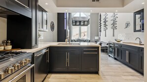Une cuisine moderne avec des meubles de couleur sombre, des appareils électroménagers en acier inoxydable et un grand îlot central.