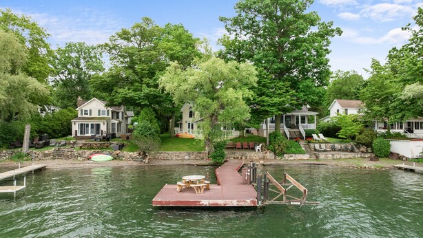 A dock with a picnic table, a stone wall, and houses with a lake view. - Twilight Cove: "Beautiful Sunset Views on Canandaigua Lake!" (Canandaigua)