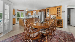 A spacious kitchen with wooden cabinets, a central island, and a dining area with chairs. - Twilight Cove: "Beautiful Sunset Views on Canandaigua Lake!" (Canandaigua)