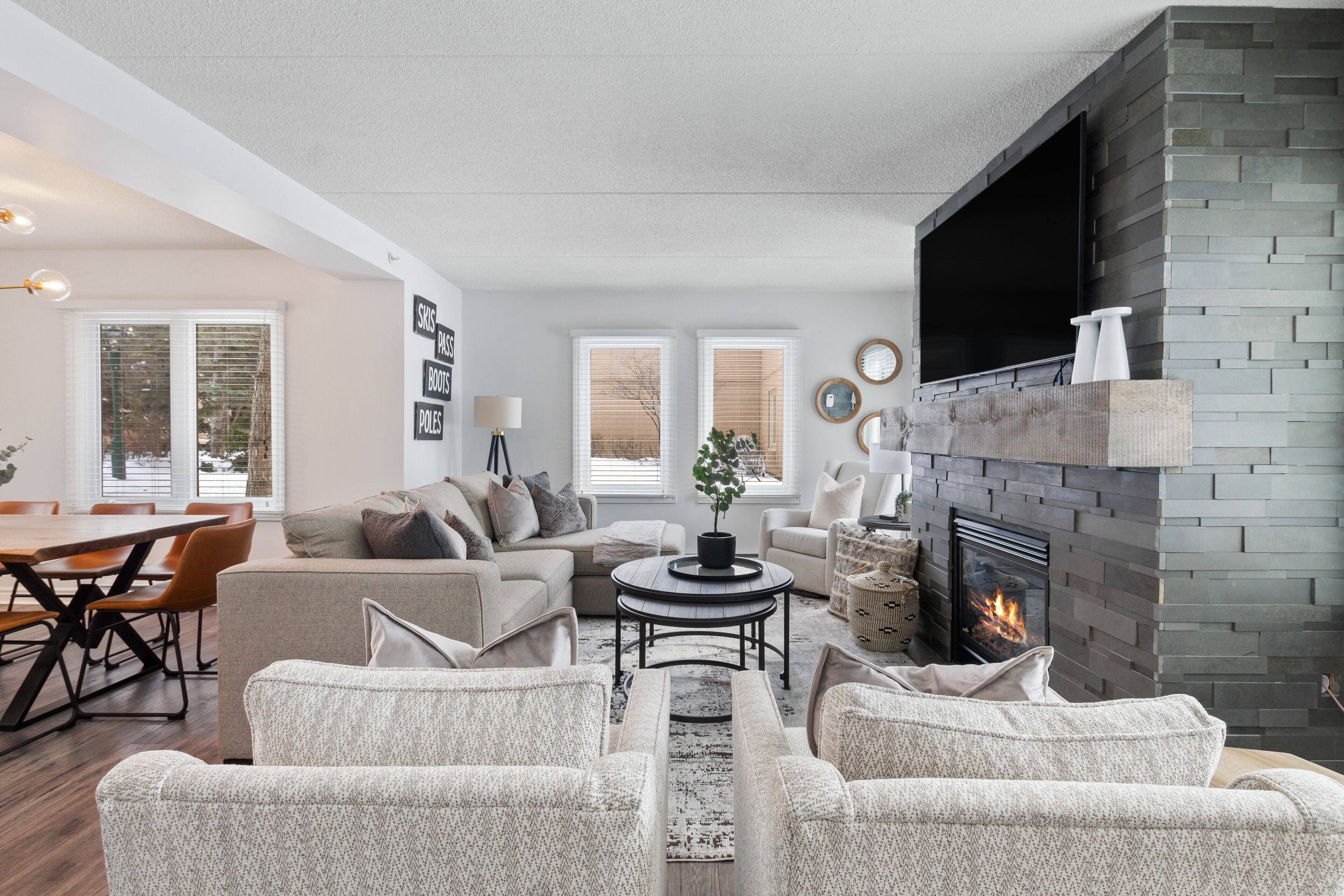 A modern living room with a fireplace, a dining area with a wooden table and chairs, and a cozy seating area with sofas and a coffee table.