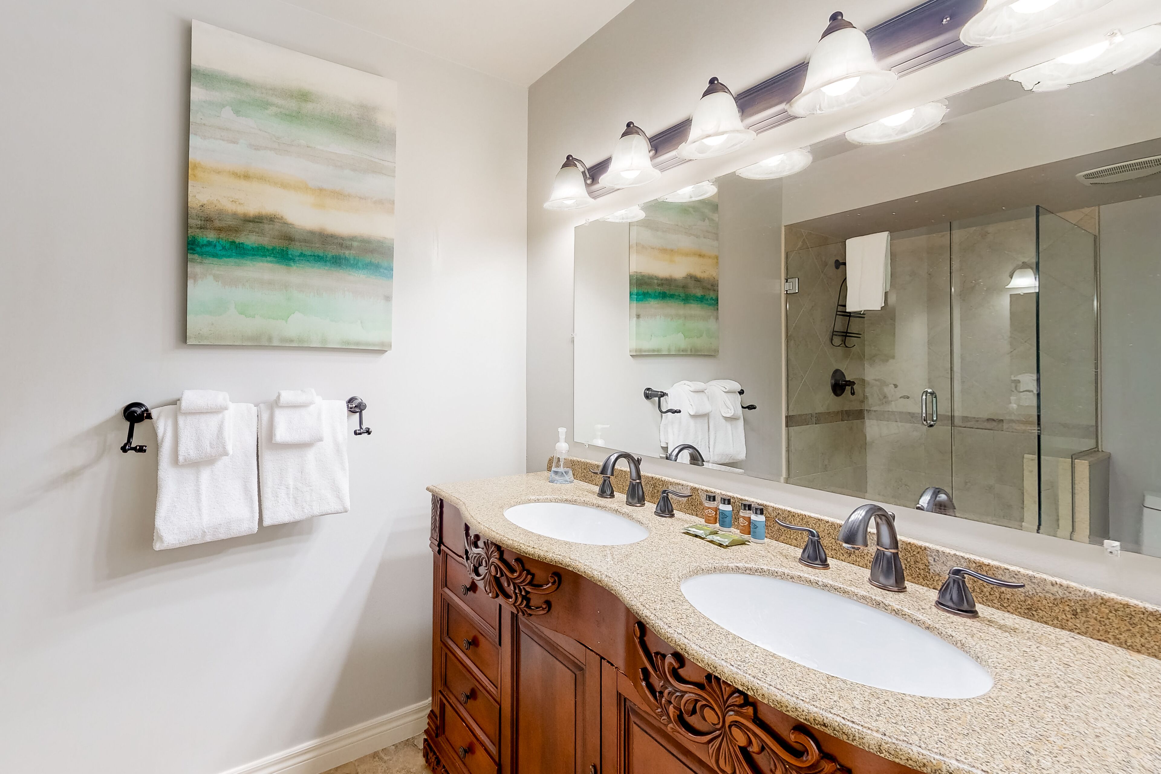 A bathroom with two sinks, a large mirror, and a glass shower enclosure.
