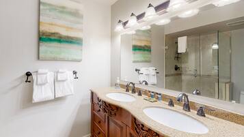 A bathroom with two sinks, a large mirror, and a glass shower enclosure.