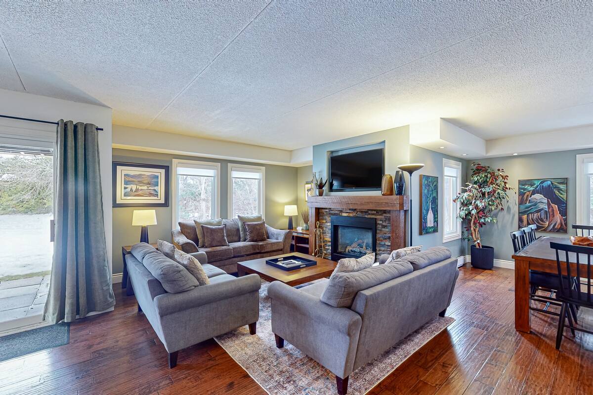 A modern living room with a fireplace, comfortable seating, and artwork on the walls.