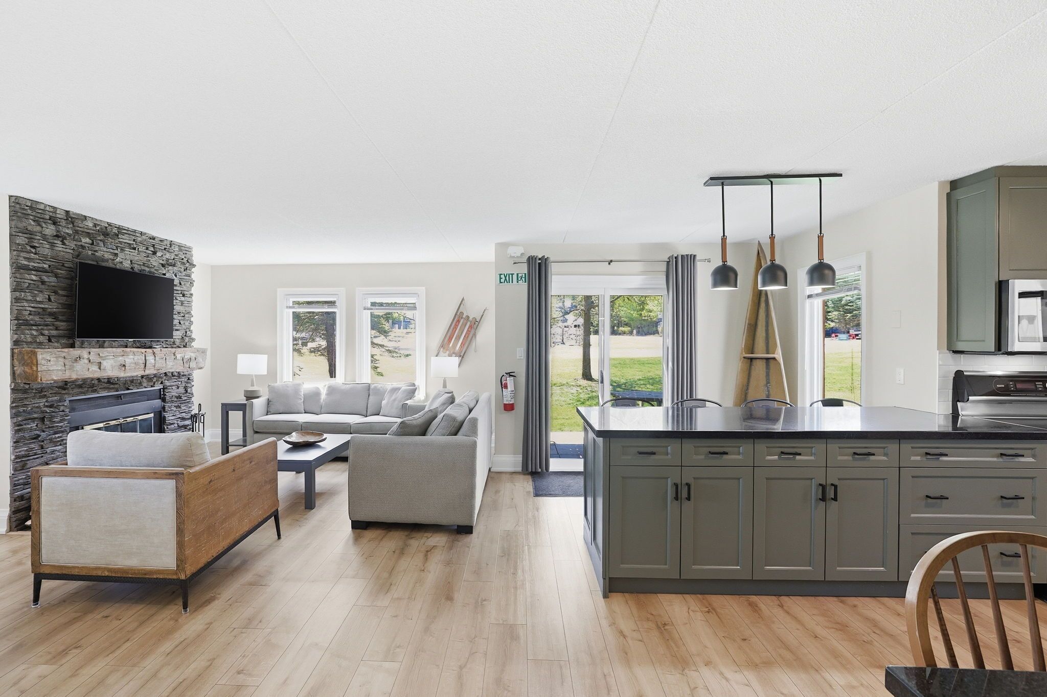 A modern kitchen with grey cabinets, a built-in oven, and pendant lighting.