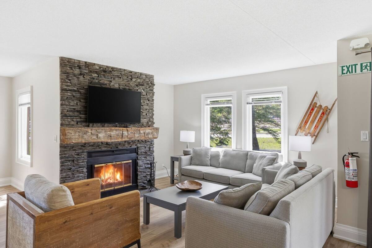 A living room with a stone fireplace, a flat-screen TV, a sofa, and a coffee table.