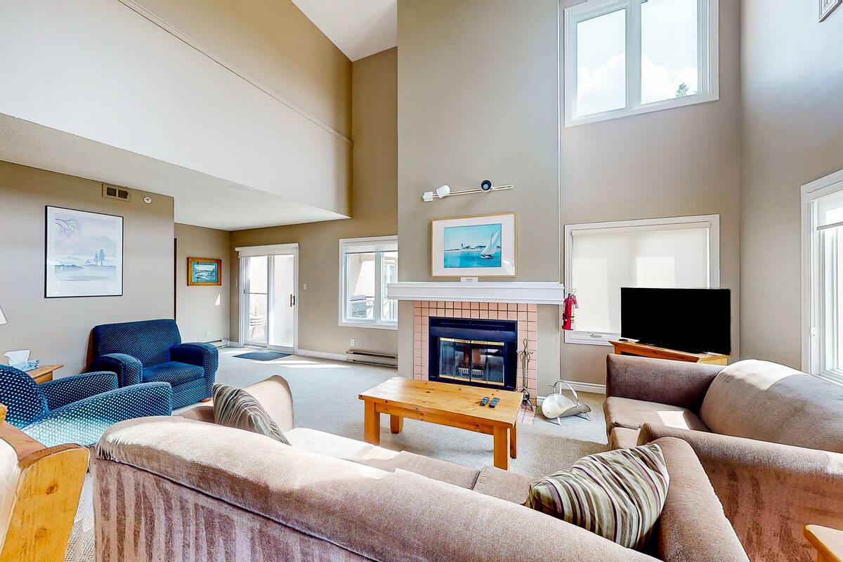 A spacious living room with a fireplace, comfortable seating, and artwork on the walls.