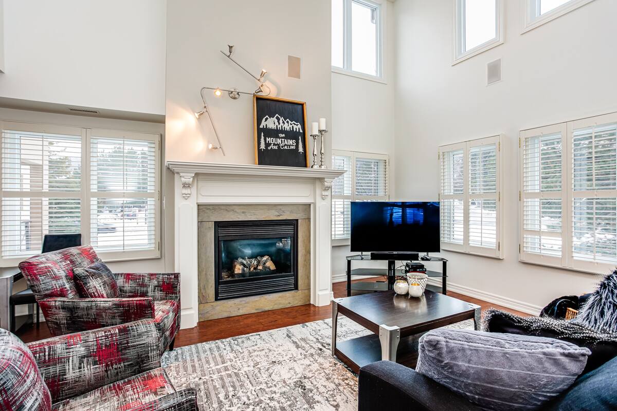 A living room with a fireplace, a television, and a large window.