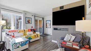 A modern living room with a sofa, a coffee table, and a TV mounted on the wall.