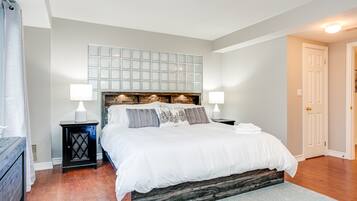 Une chambre à coucher avec un grand lit, deux tables de chevet, une commode, un panneau décoratif au mur et une porte.