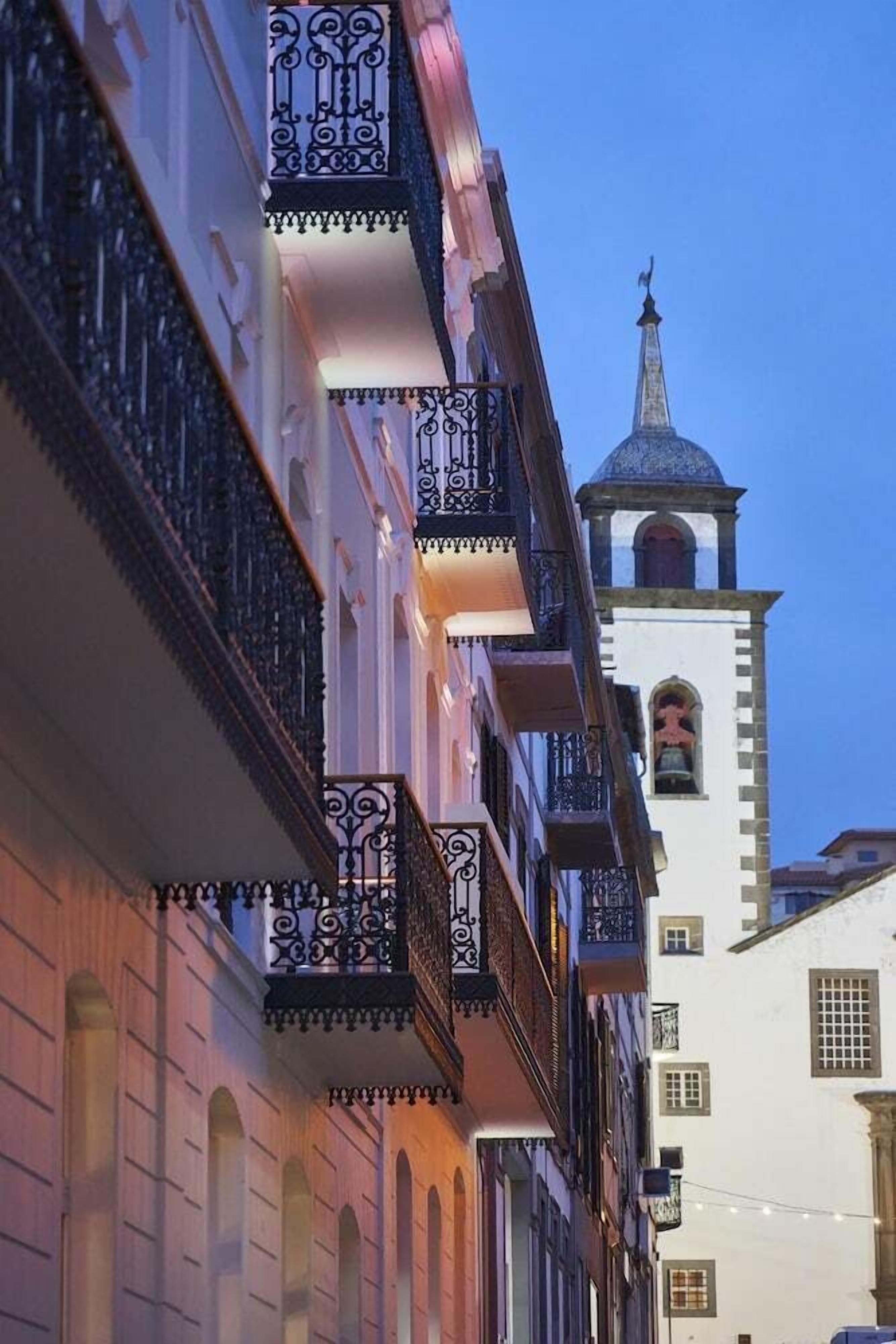 Un edificio con balcones decorativos y una torre con campana.