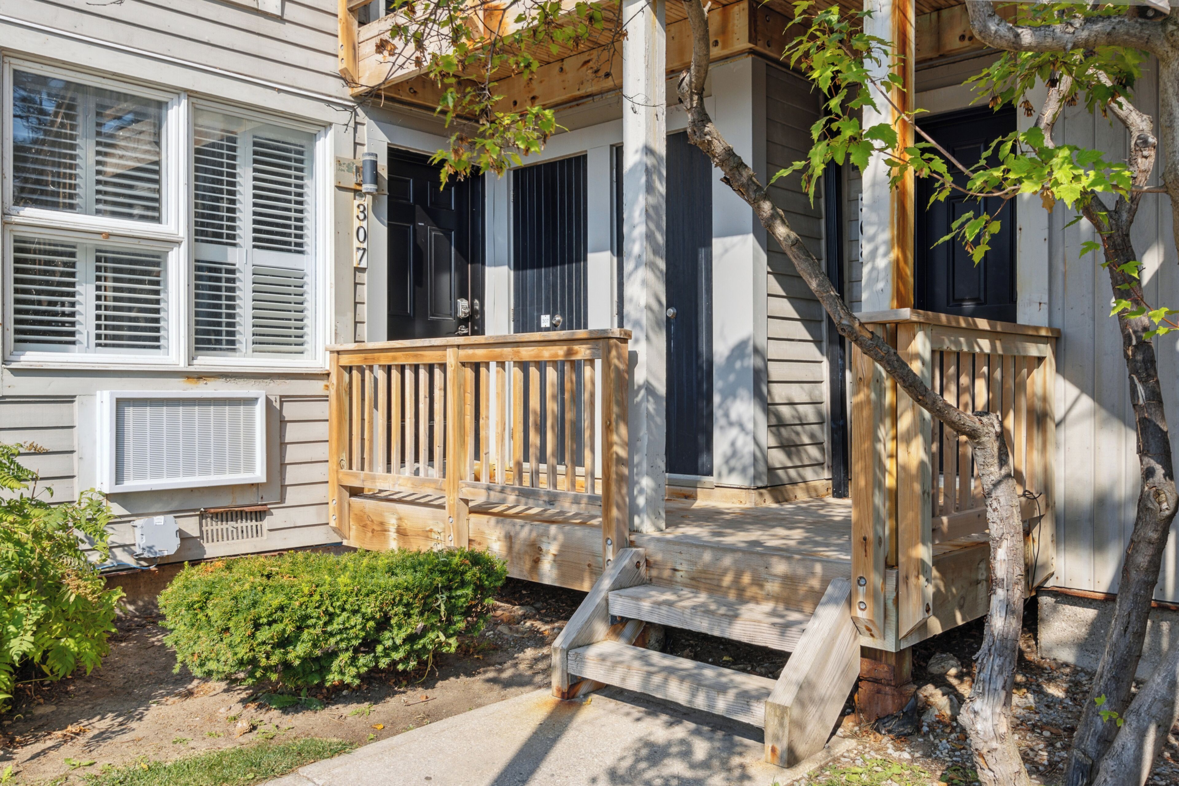 A two-story house with a wooden porch and a small garden.