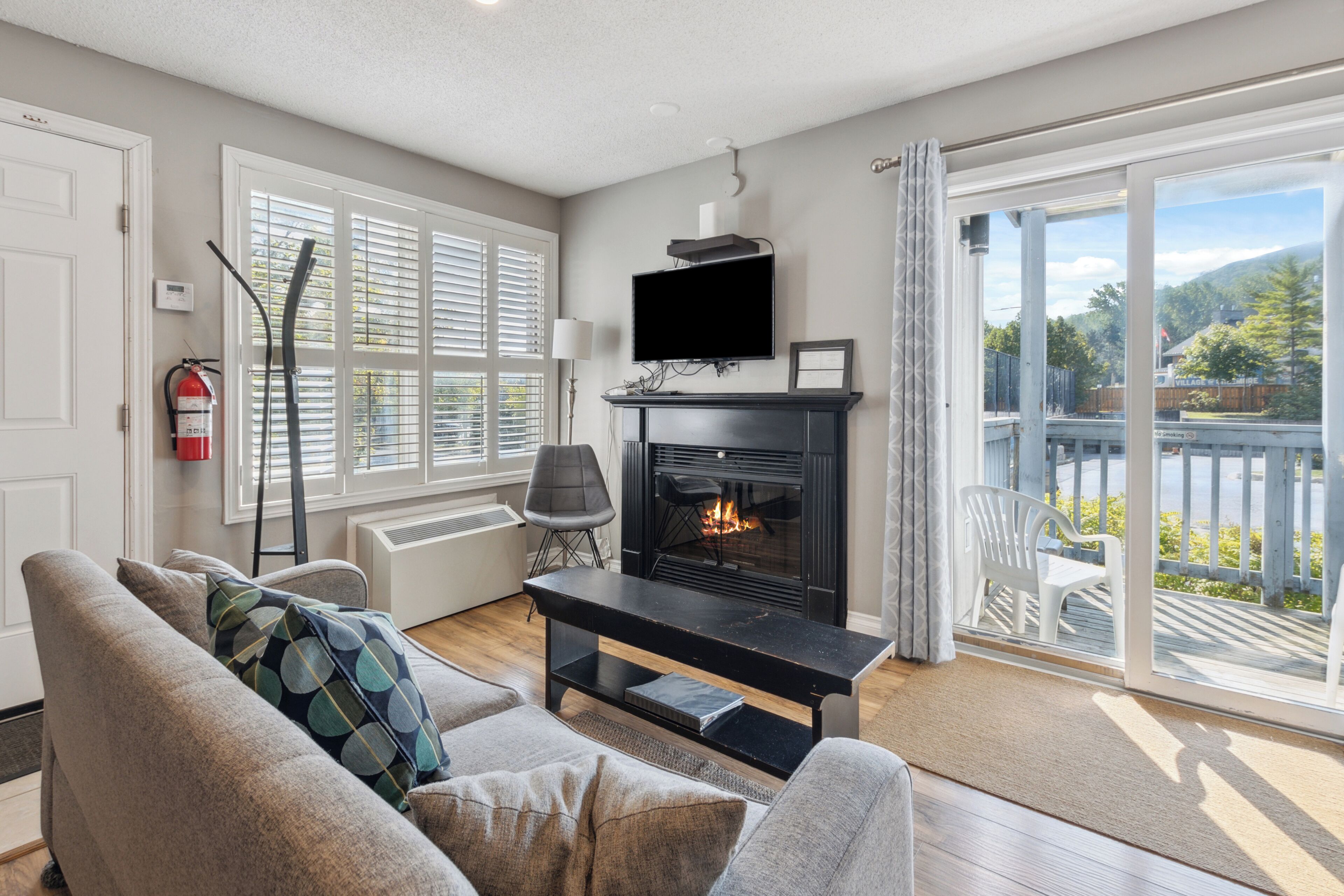 Una sala de estar con chimenea, televisor y vistas al exterior.