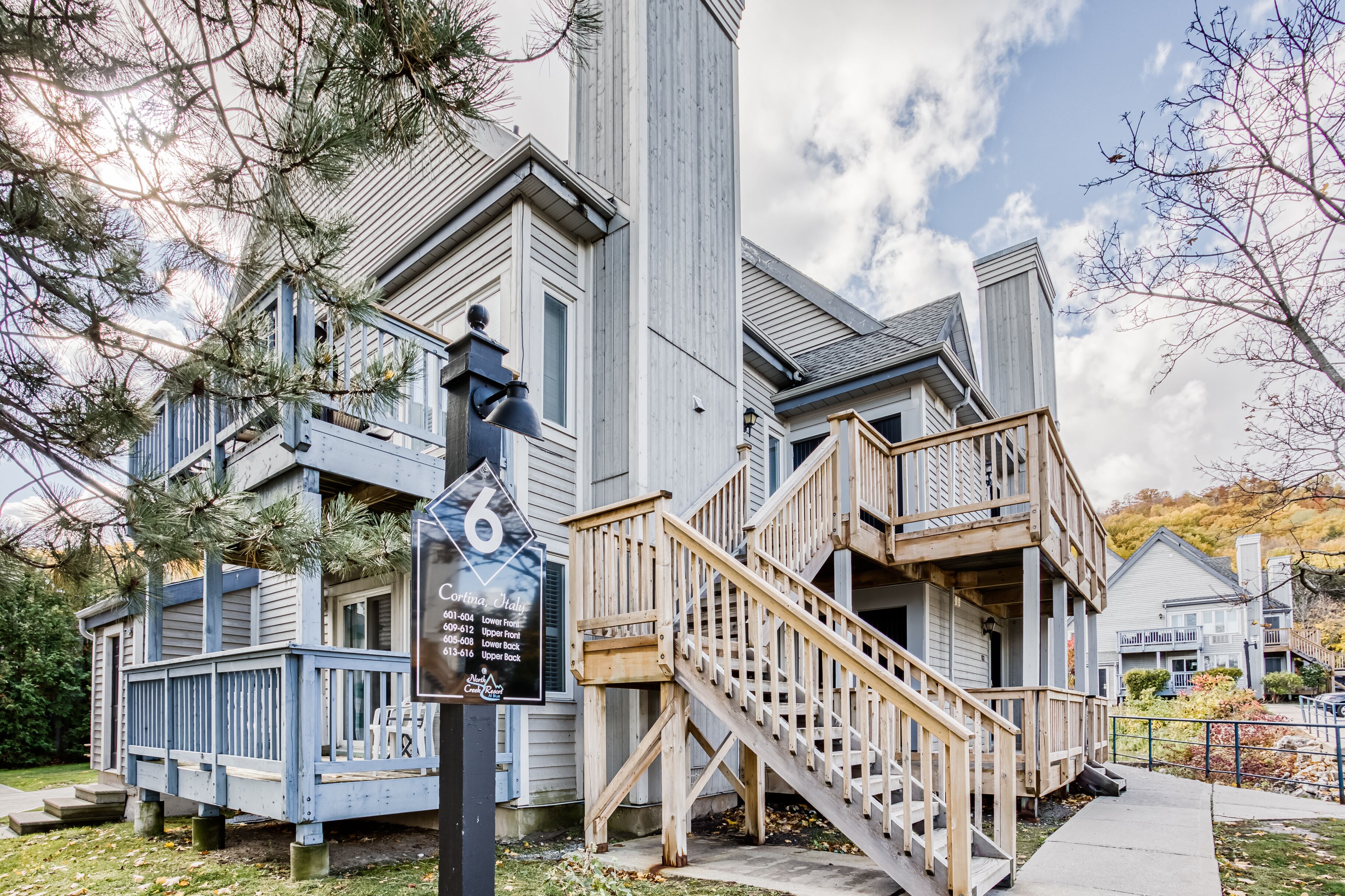 Une maison en bois à deux étages, dotée d’un porche à l’avant, d’un escalier et d’une enseigne indiquant l’adresse.