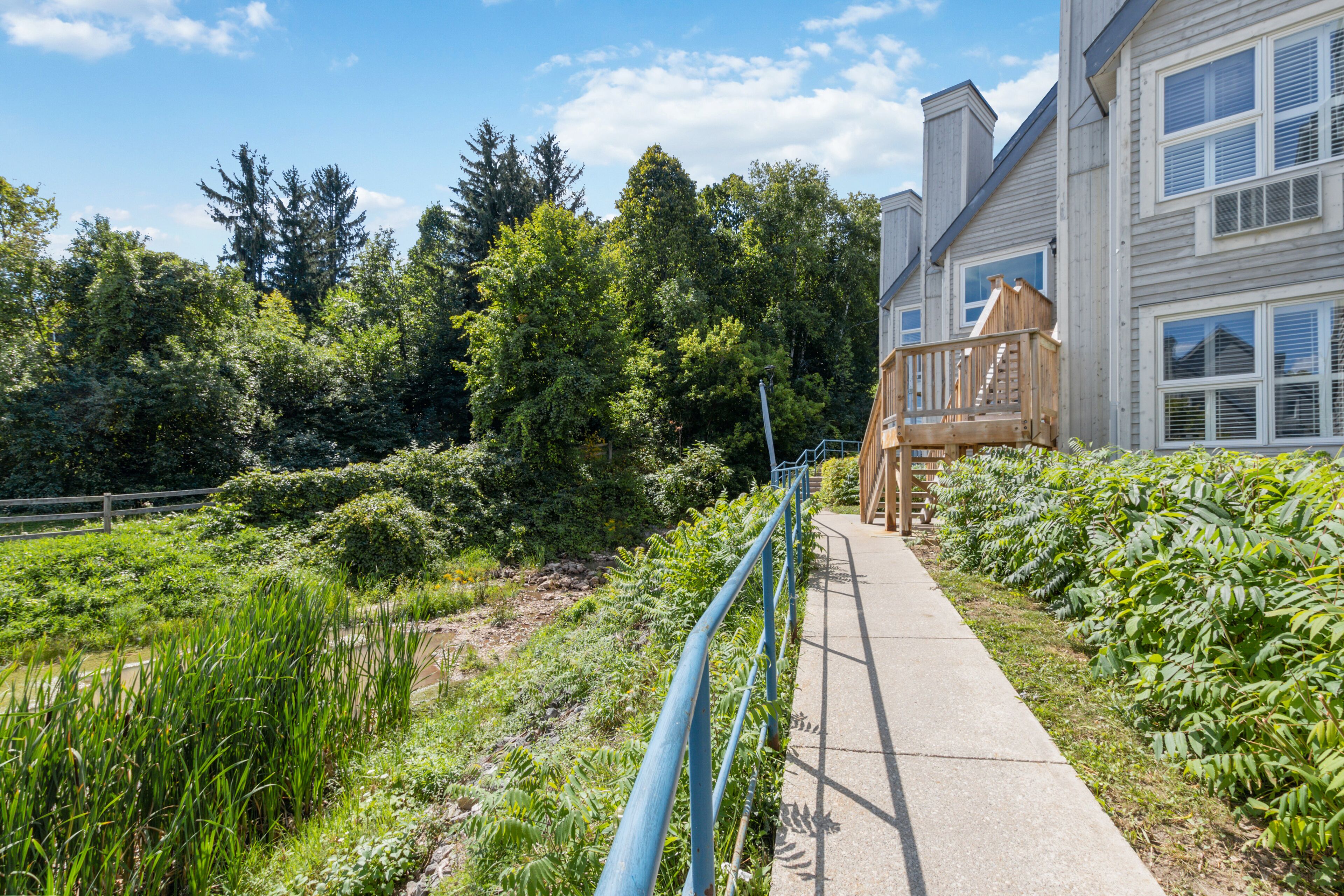 A pathway leading to a building with a wooden deck and a staircase.