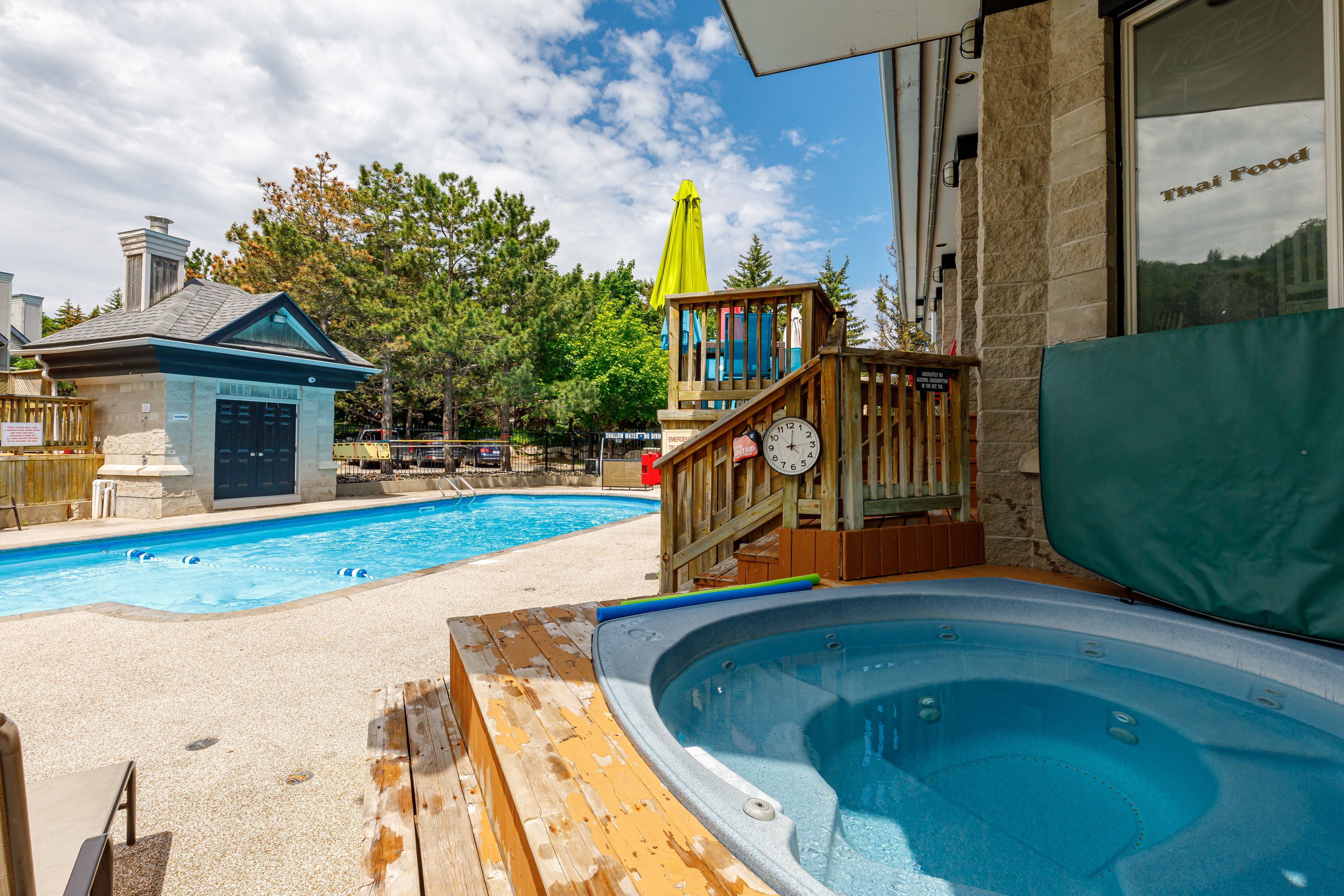 A swimming pool with a hot tub, wooden deck, and a building labeled "Thai Food".