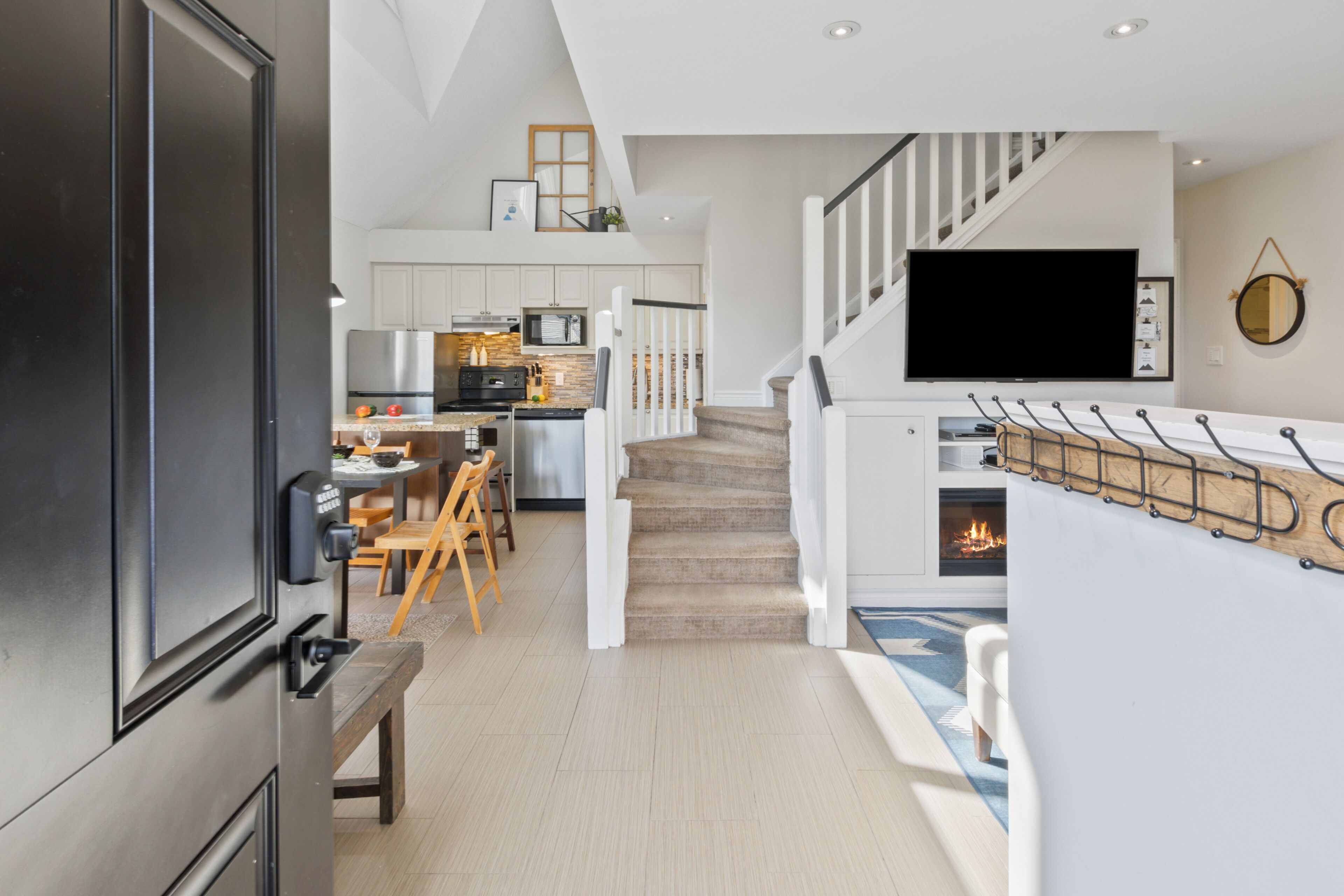 Una cocina moderna con armarios blancos, horno integrado y comedor con sillas de madera.